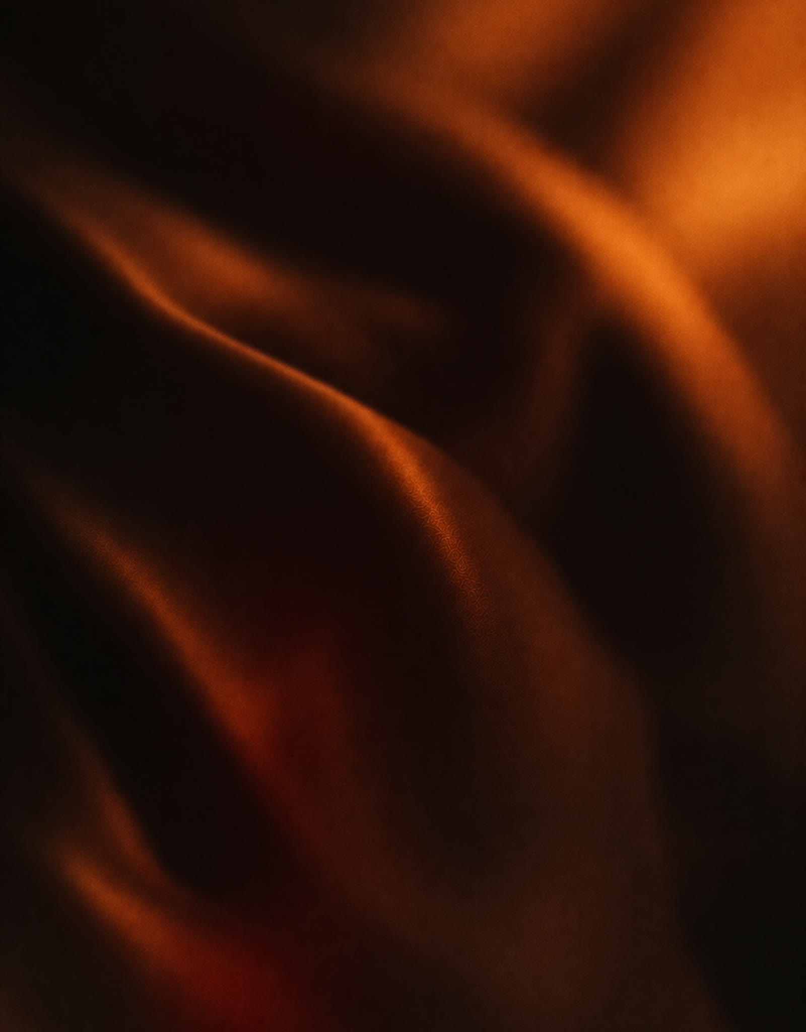 Folds of dark fabric catching warm amber light